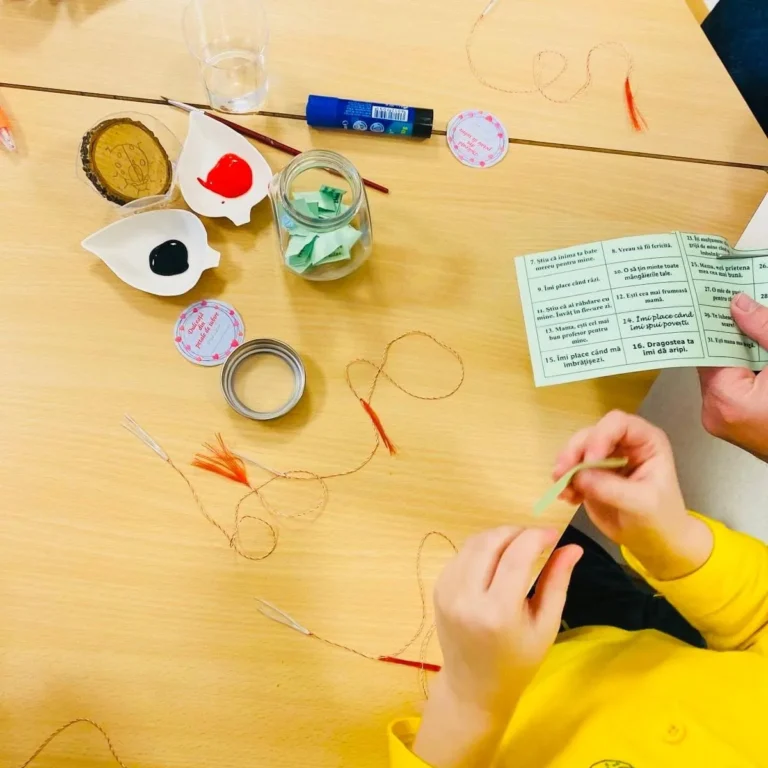 Mâini de copil lucrând cu ață și materiale colorate, la un atelier de la Grădinița Amicus Junior din Iași