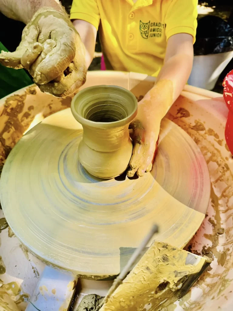 Mâini de copil modelând lut la roata olarului, într-un atelier de la Grădinița Amicus Junior din Iași