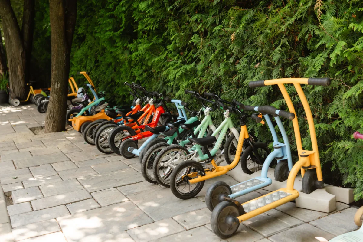 Biciclete fără pedale și trotinete aliniate pe aleea din curtea Grădiniței Amicus Junior din Iași
