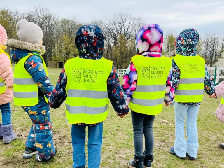 Copii văzuți din spate, în veste reflectorizante Amicus Junior, într-o ieșire în afara grădiniței