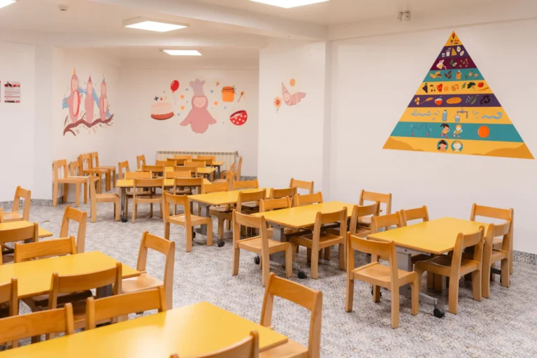 Sala de mese cu mese și scaune de lemn adaptate vârstei preșcolare, la Grădinița Amicus Junior din Iași
